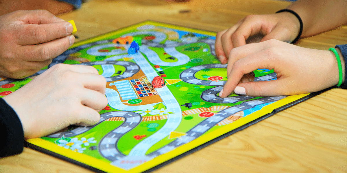 Close-up photo of hands moving game pieces around a brightly colored board game