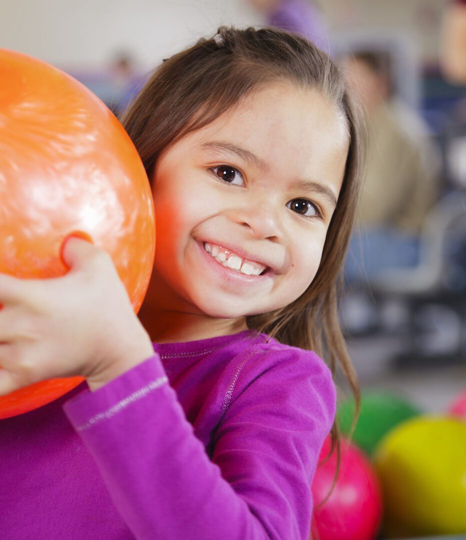 A little girl holding a bowling ball.
