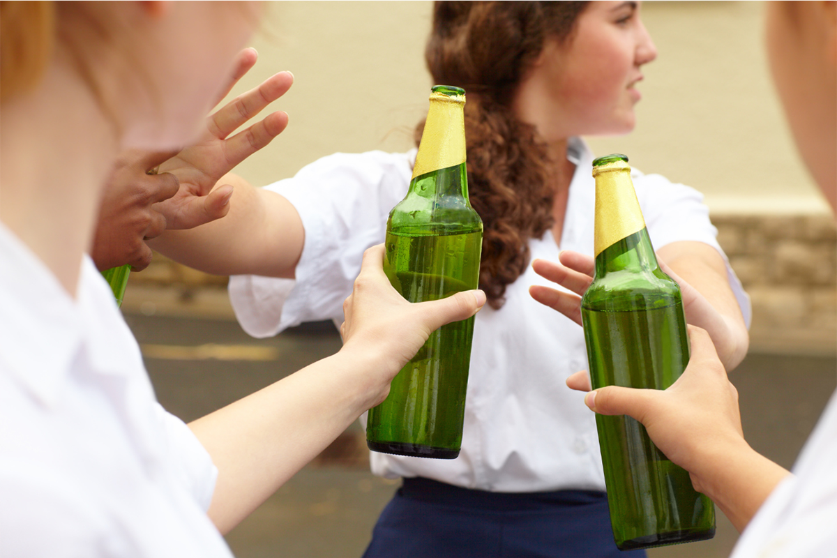 Teenage girl being pressured to drink beer.