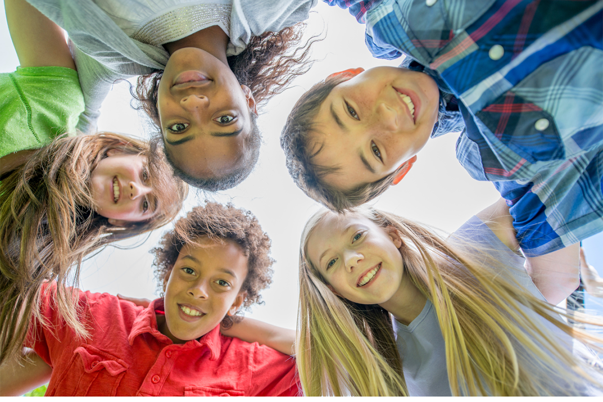 A group of middle school aged children in a circle looking down at the camera.